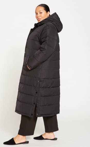 model showing a side view of the black coat and how it unbuttons at the side