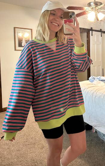 A reviewer successful  a pinkish  and greenish  striped crewneck with yellowish  ringer accents 