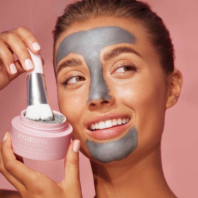 model wearing the face mask and holding the product and brush