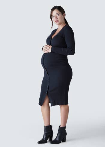 model posing, showing off belly in black sweater dress