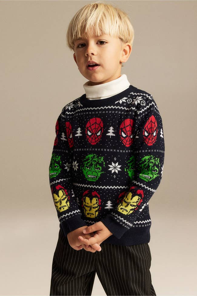 a child in a marvel holiday sweater with spider-man, the hulk, and iron man on it