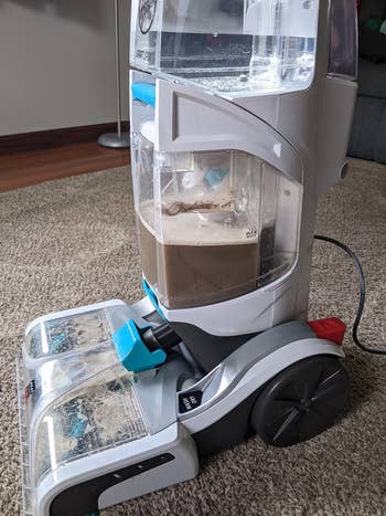 Upright carpet cleaner with dirty water indicating recent useg
