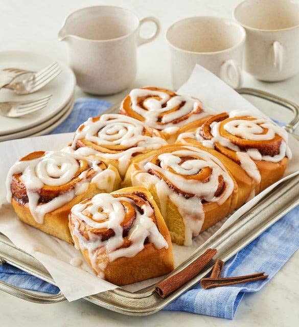 A tray of six cinnamon rolls topped with icing.