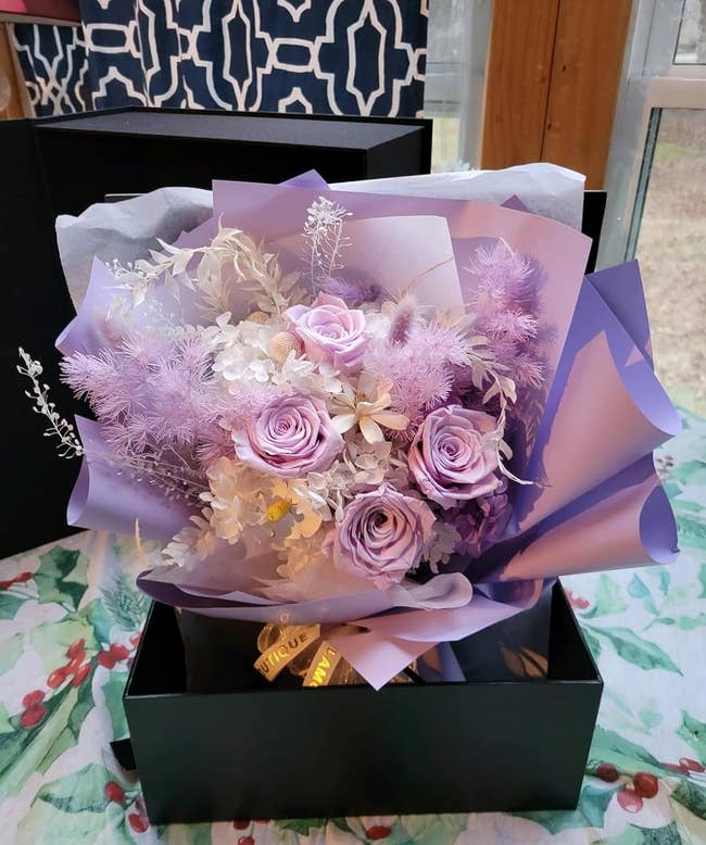 reviewer's bouquet of purple and white flowers with presented in a black gift box