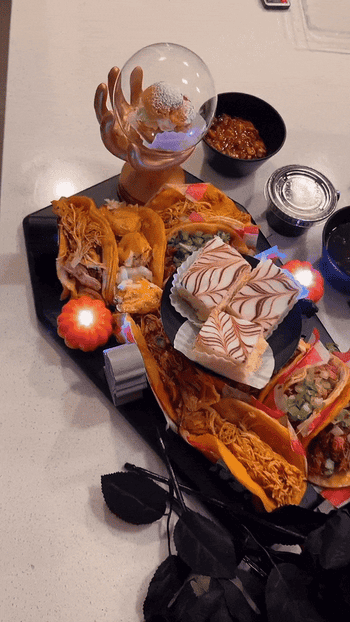 a coffin shaped charcuterie board with decorations, tacos, and desserts on it
