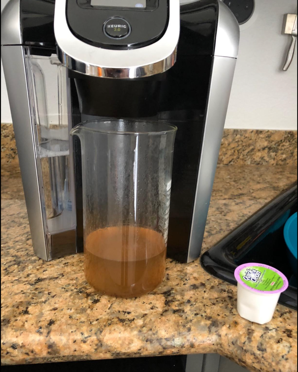 A Keurig cleaning pod next to a mucked up bit of water that came out of the machine 
