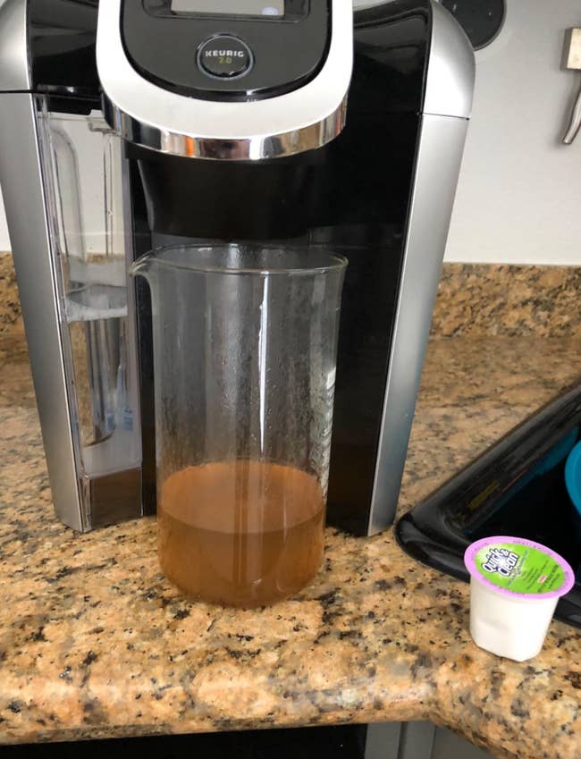 A Keurig cleaning pod next to a mucked up bit of water that came out of the machine 