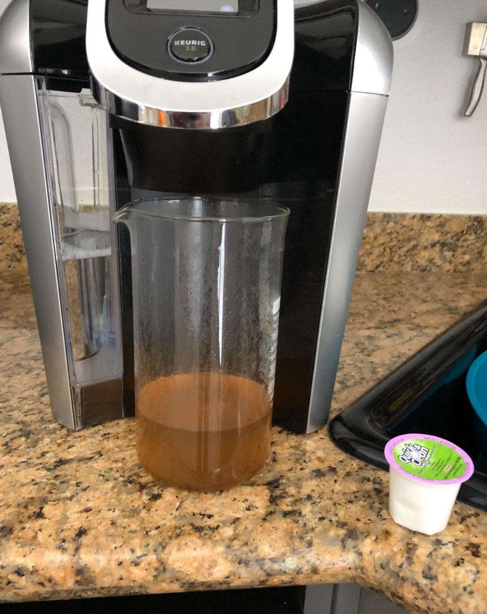 A Keurig cleaning pod next to a mucked up bit of water that came out of the machine