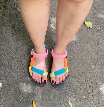 Person wearing colorful sandals with multicolored straps portion    lasting  connected  a paved surface