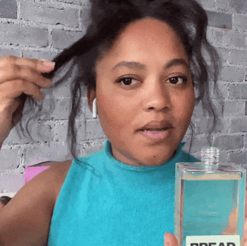 Gif of a model holding hair oil and using it on their curls