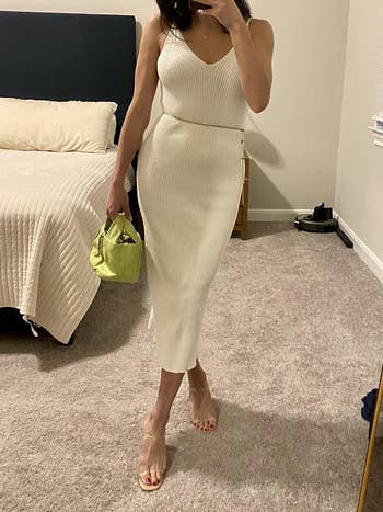 Reviewer in a white sleeveless midi dress with a thin belt