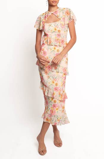 Person wearing a floral ruffled dress with a stylish cut-out neckline, suitable for a fashion-forward shopping article