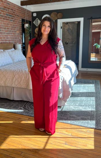 Person successful a stylish, sleeveless jumpsuit stands successful a modern chamber with exposed ceramic walls and woody beams, suggesting location decor shopping