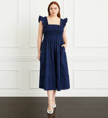 Model in a flutter sleeved tiered navy blue maxi dress with smocking at chest 