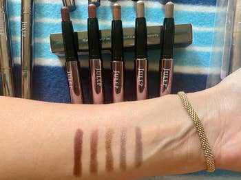 Person swatching five shades of Julep eyeliners on their arm with product array visible