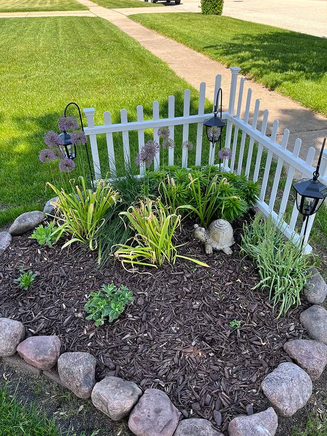 small white pickett fence corner around some plants and rocks