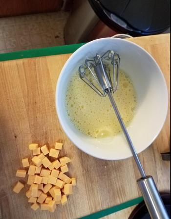 reviewer's whisk next to a bowl of mixed eggs 