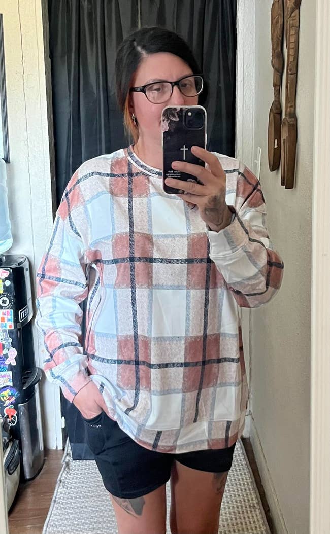 Person taking a reflector  selfie, wearing a plaid apical  and achromatic  shorts, successful  a casual setting