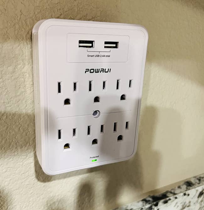 POWRUI surge protector with USB ports plugged into a wall outlet 