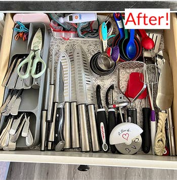 same reviewer's after photo, showing the drawer looking much more orderly and spacious now that the utensils are in the tiered organizer