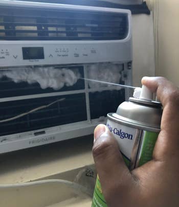 reviewer spraying an air conditioner with the foaming spray