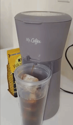Reviewer using product with coffee dispensing into tumbler with ice