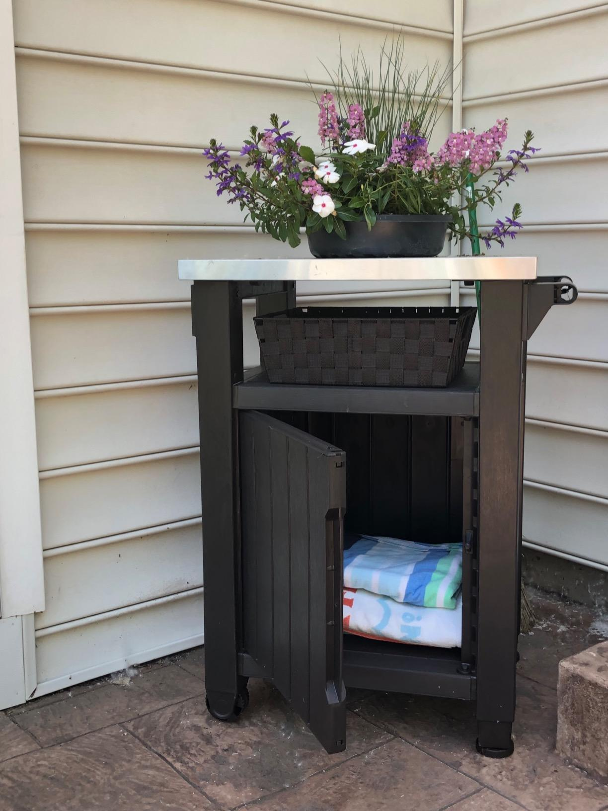 another reviewer's outdoor cart holding gardening supplies with cabinet open showing storage