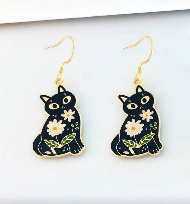 gold and black cat drop earrings with daisies on them