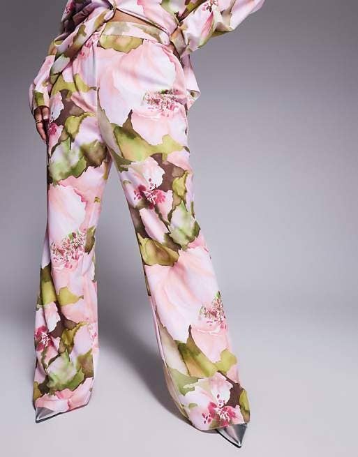Floral-patterned wide-leg pants with an abstract design, worn with a matching top and metallic pointed shoes