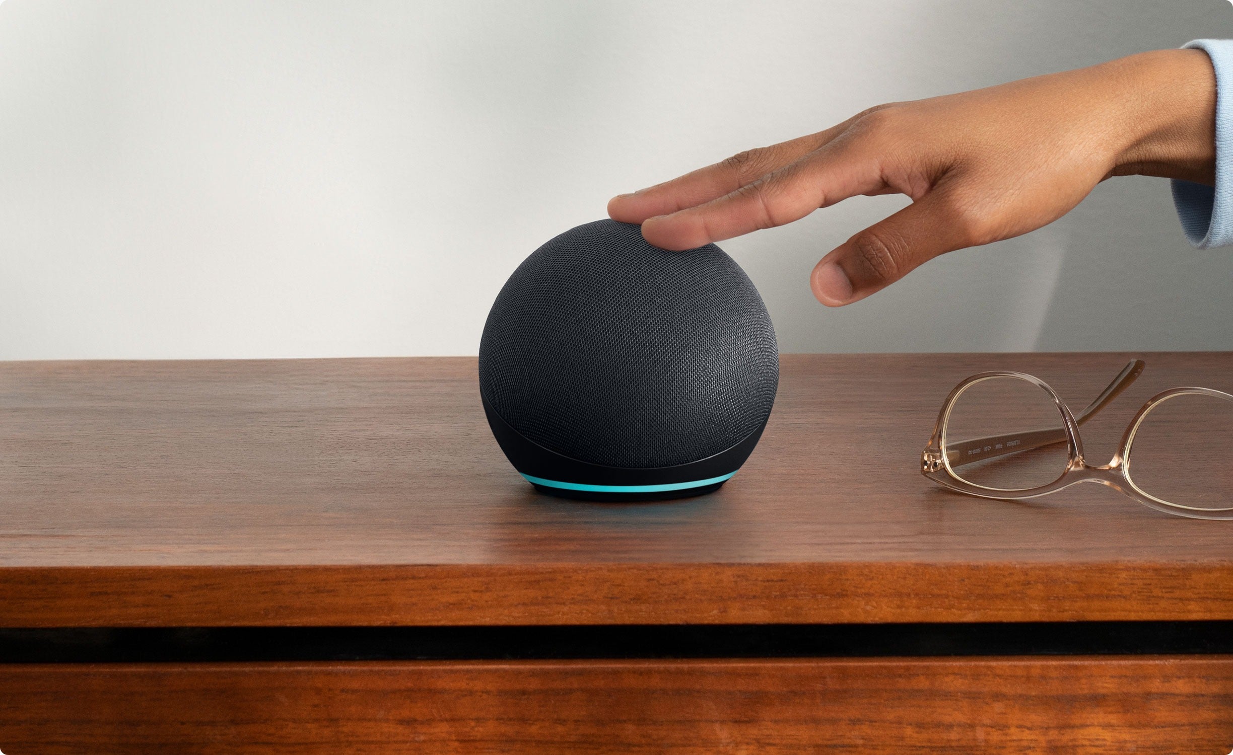 a model's hand reaching out to touch the charcoal echo dot
