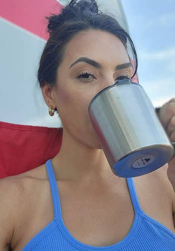 a reviewer wears the smallest gold hoops while holding a mug