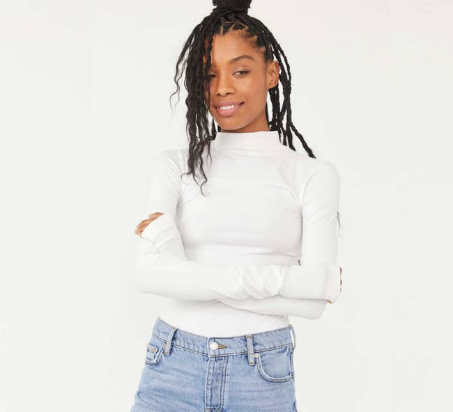 Model is wearing a white turtleneck and denim jeans