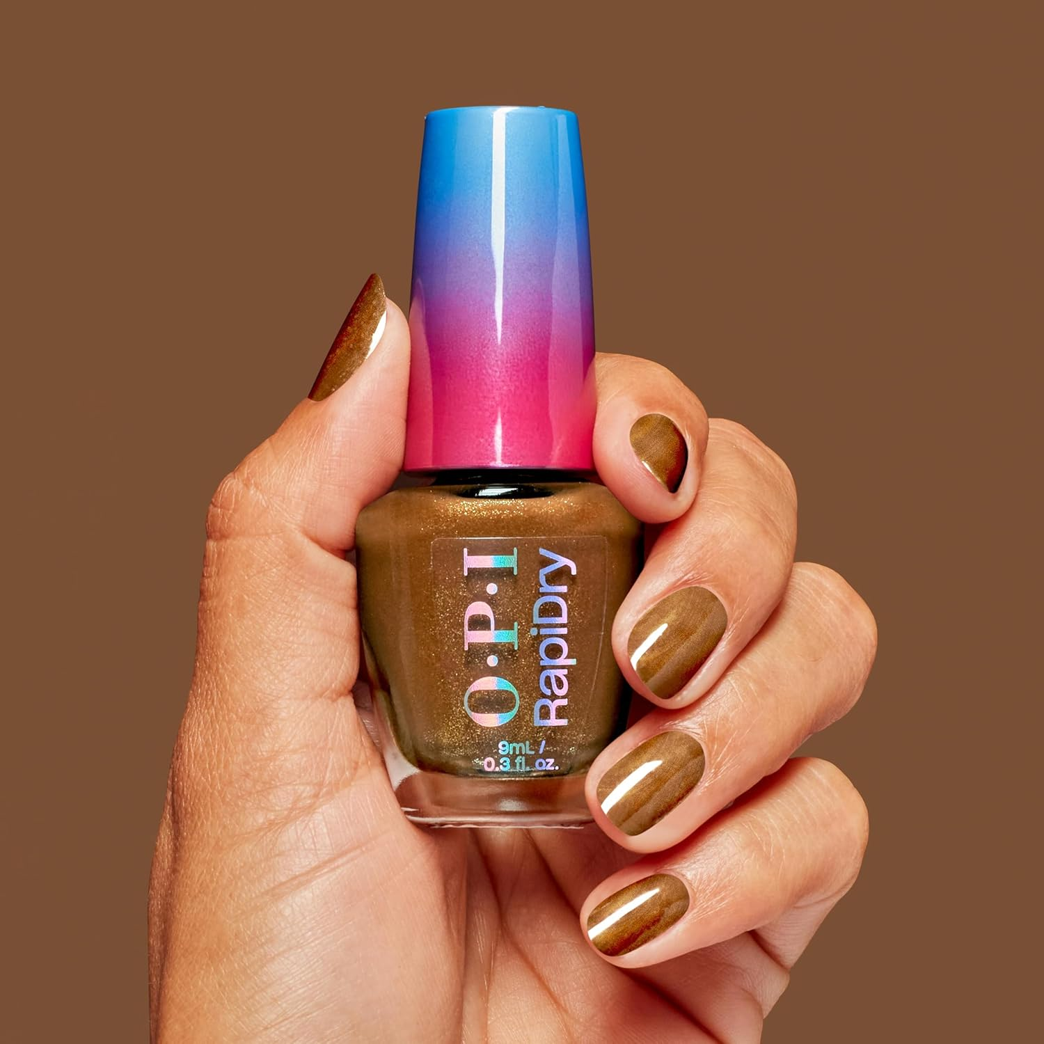 Hand holding a bottle of OPI RapidDry nail polish; nails painted in matching brown shade