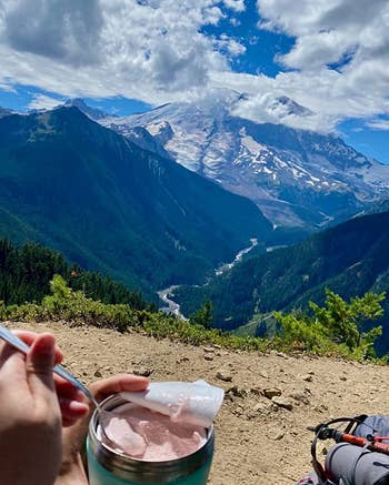 a reviewer eating ice cream out of the blue pint cooler while on a hike 