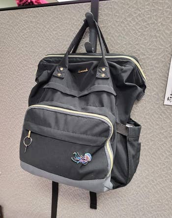 Black backpack hanging on a hook on a cubicle wall 