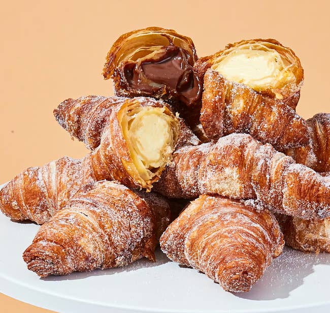 Assorted croissants filled with cocoa and cream, stacked connected a achromatic plate, perfect for gourmet buying enthusiasts
