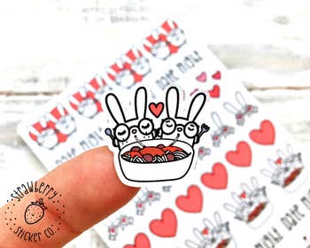 fingertip size sticker that looks like two bunnies sharing spaghetti and meatballs