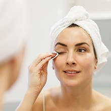 Person successful  a bath  utilizing a fabric  pad connected  the face, wearing a towel wrapper  connected  the caput  and a achromatic  vessel  top, suggesting skincare routine