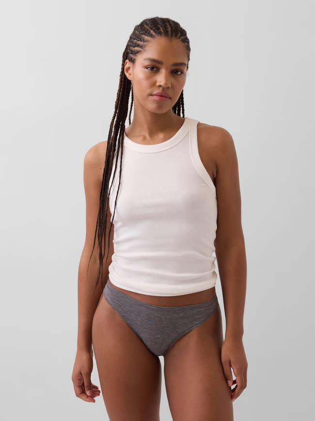 Person successful a sleeveless achromatic ribbed vessel apical and grey underwear, lasting confidently