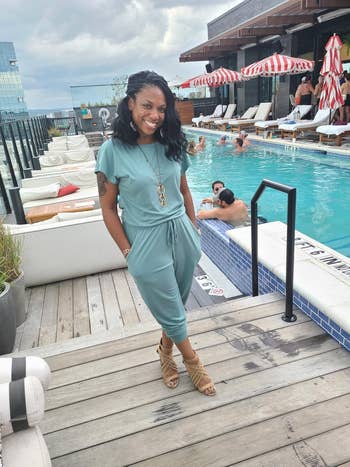 Person successful  a casual jumpsuit and sandals stands connected  a rooftop excavation  platform  with lounge chairs and umbrellas successful  the background