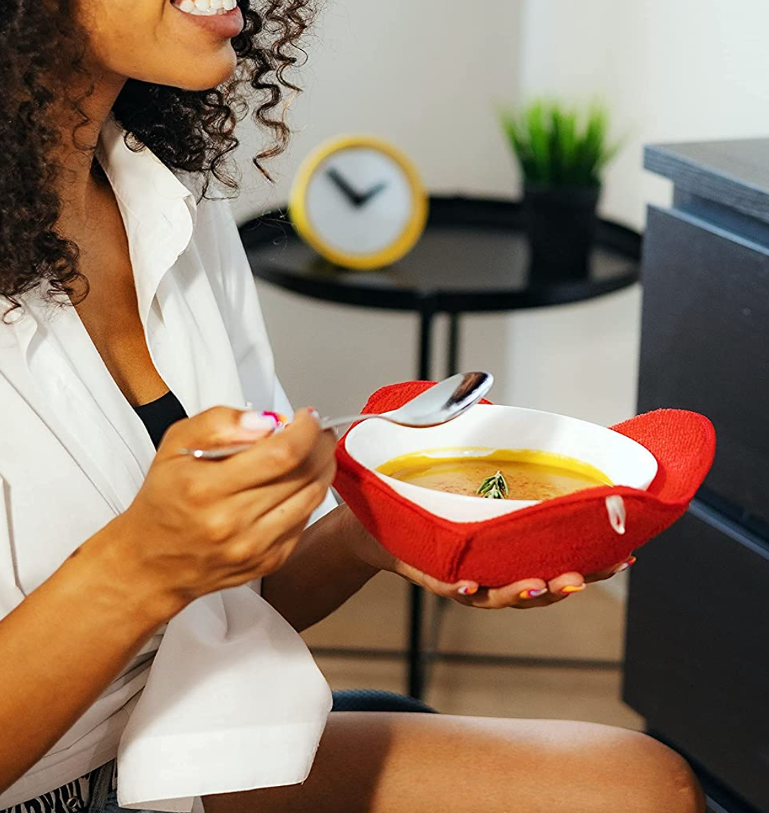 Model holding a bowl of soup resting in a red cloth holder 