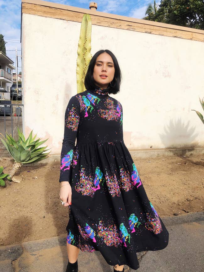 a model wearing the long sleeve dress that is black with colorful designs all over it 