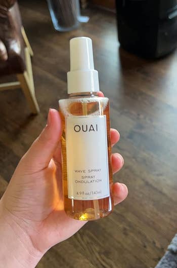 Reviewer holding a bottle of OUAI Wave Spray hair product