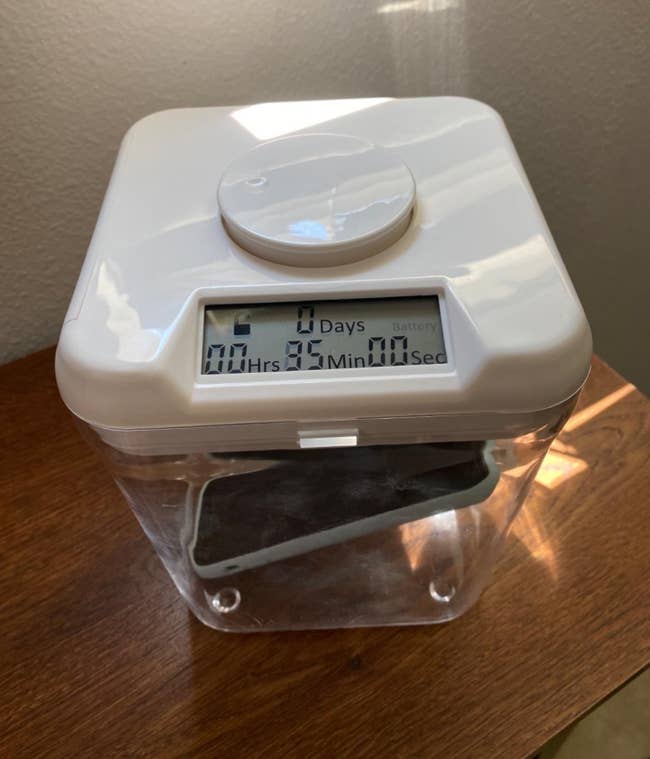 Time-lock container on a wooden surface with its digital display showing