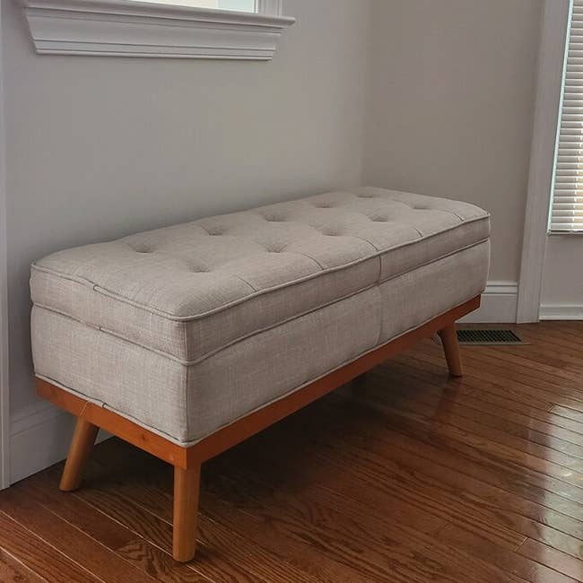 reviewer's gray storage bench with wooden legs