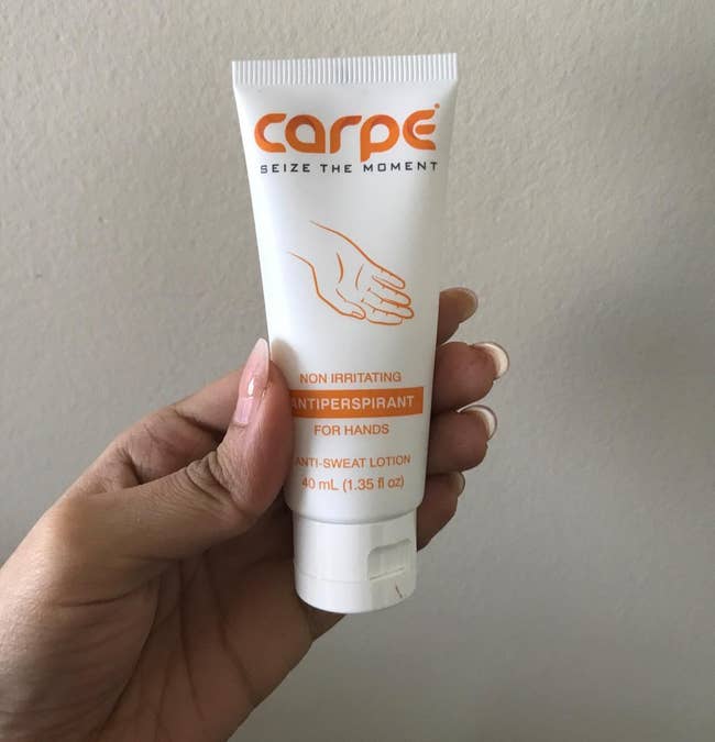 reviewer holding the tube of hand cream