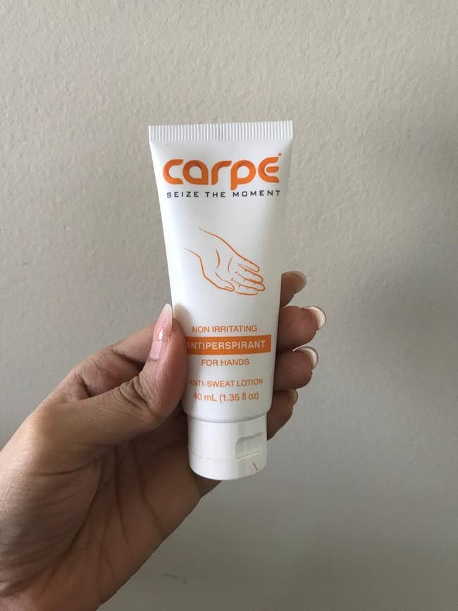 reviewer holding the tube of hand cream