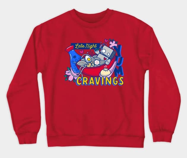 a red crewneck sweatshirt featuring a robot sitting in a bowl of ramen and text reading 
