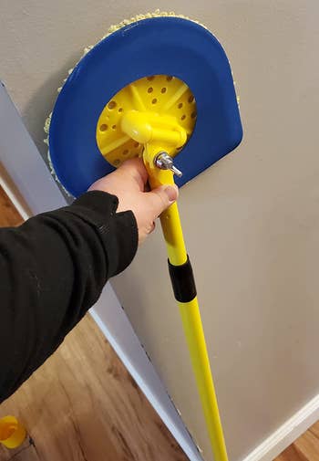 reviewer holding the yellow and blue mop upright