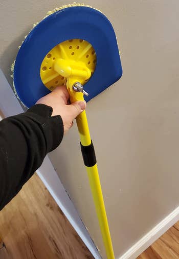 reviewer holding the yellow and blue mop upright